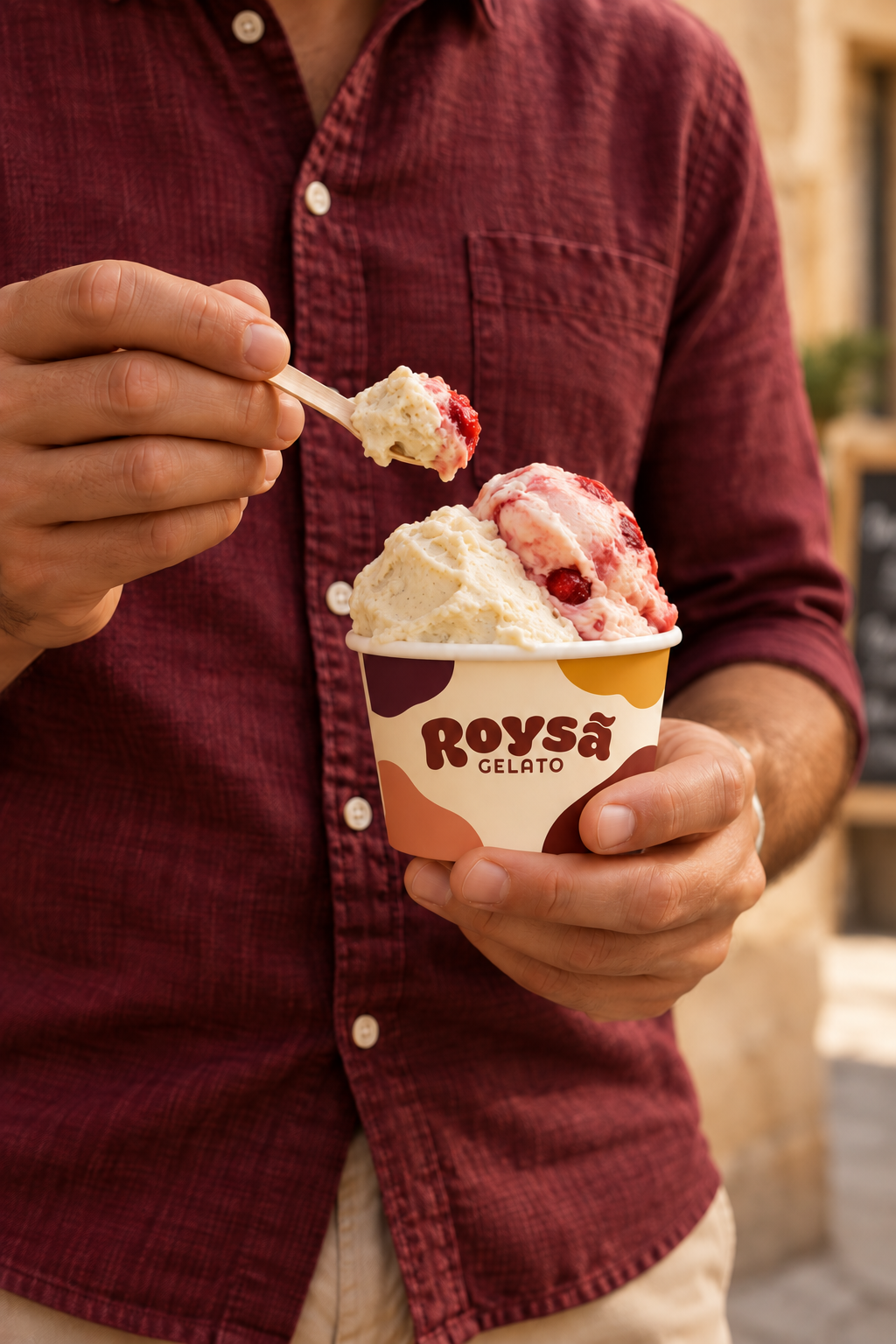 Imagem conceitual de uma pessoa com camisa vinho saboreando gelato de um copo Roysã, com a colher em destaque